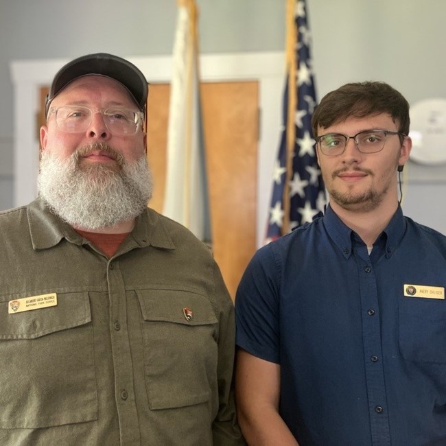 Two men stand next to each other smiling, each with an NPS name tag.