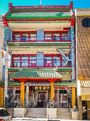 A yellow building with a red and green tiled roof and a sign with Chinese characters.