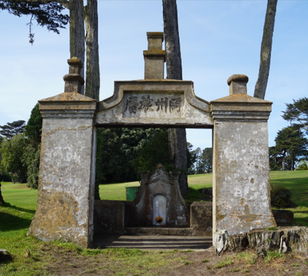 A concrete monument surrounded by trees and a green lawn.