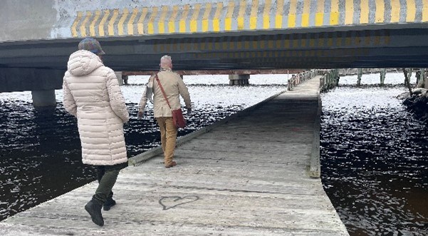 Image of two people walking along a boardwalk trail on the Cambridge waterfront.