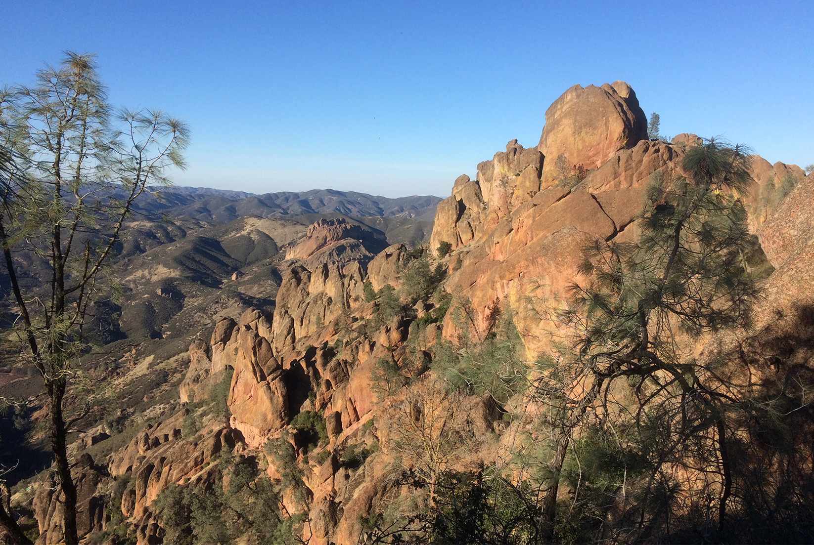 Orange sandstone rocks spires just into blue sky, mountains in distance
