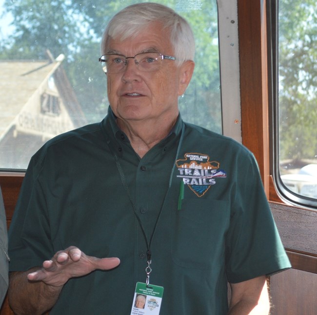 Bill Pollard speaks to someone out of frame while on a train and wearing the official Trials and Rails uniform.