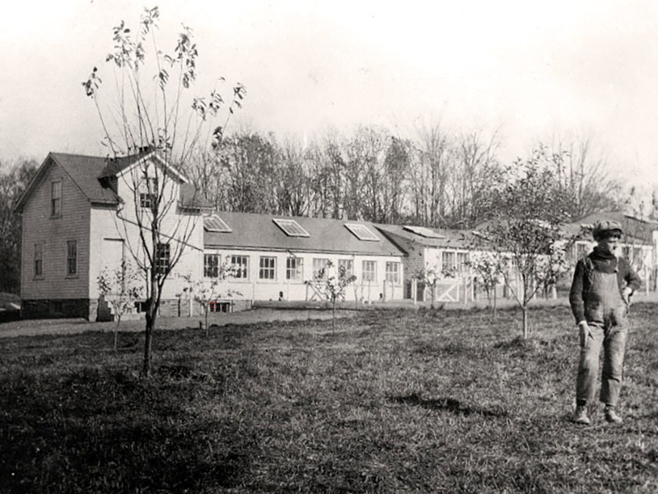 A long building with many small windows and a boy standing in the foreground.