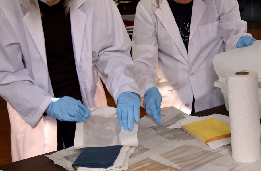 Deux spécialistes de la conservation placent des papiers absorbants entre les pages de livres mouillés.