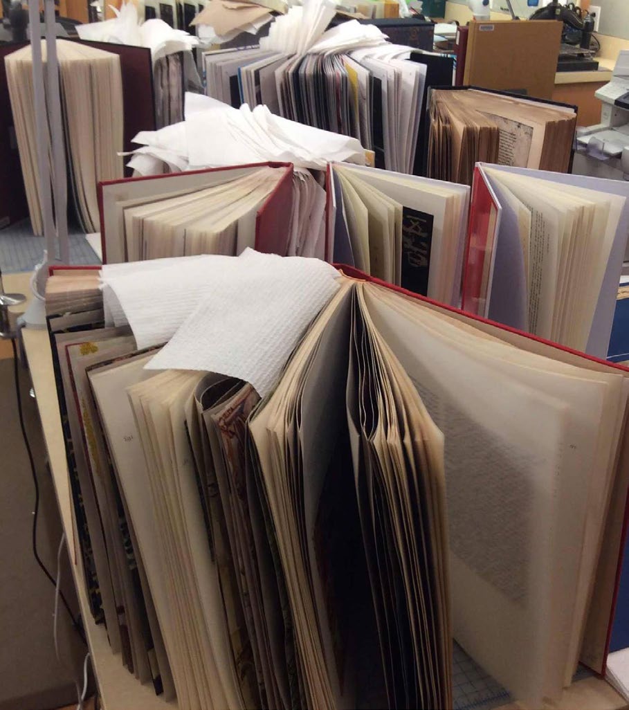 Un livre humide est entrouvert et maintenu sur la tranche, avec des feuilles absorbantes intercalées entre ses pages pour le séchage.