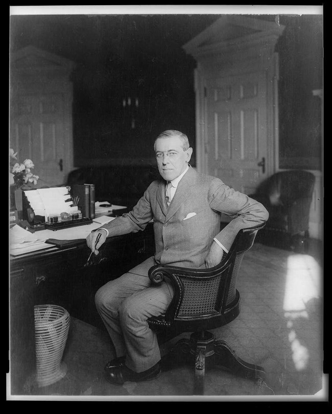 Photo portrait of President Wilson sitting at a desk