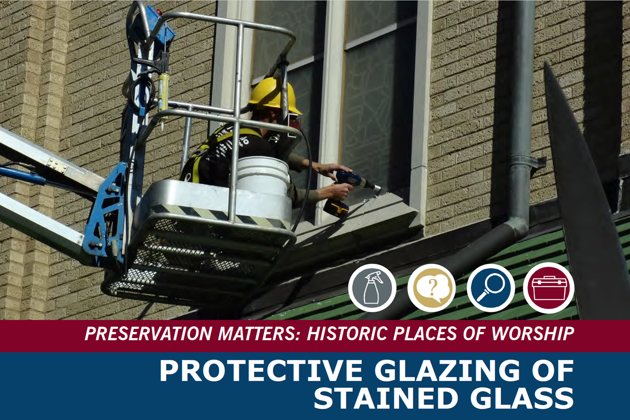 A person on a lift applies glazing to second story windows.