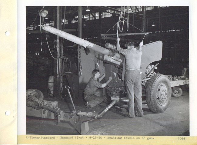 Two men mounting a shield on a 3in WW2 gun.