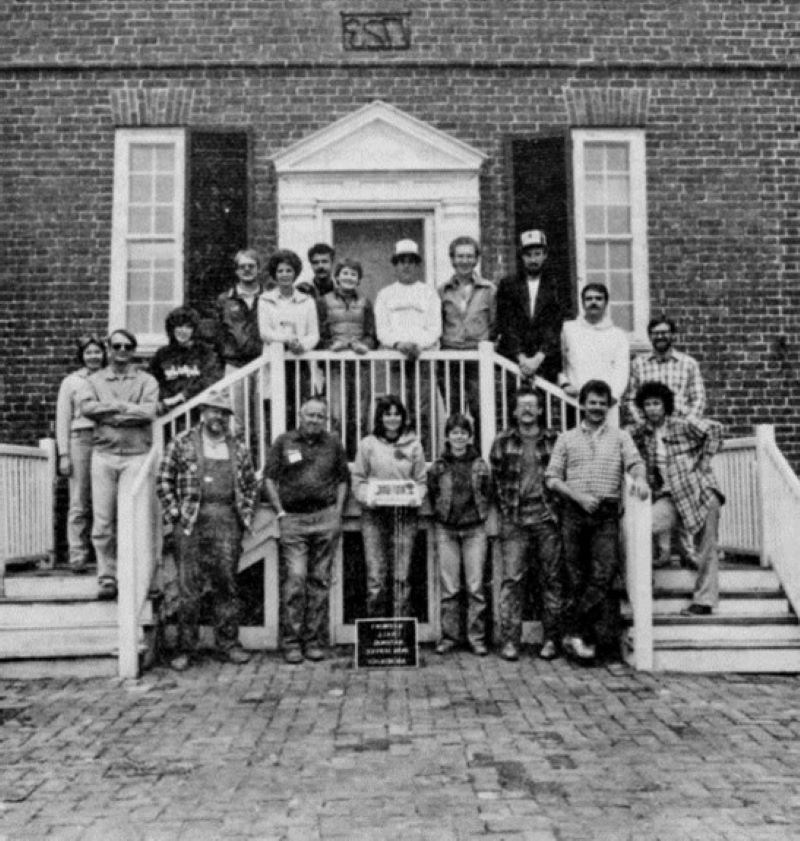 A crowd of people pose in front of a brick building