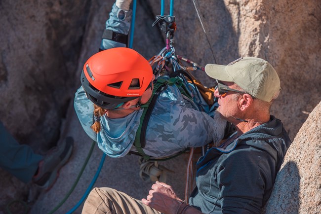 A coach instructing an adaptive climber