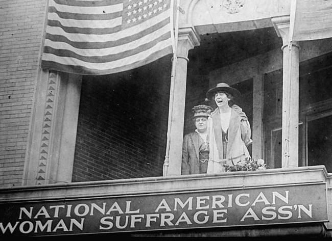 Jeannette Rankin on balcony of NAWSA with Carrie Chapman Catt standing behind her