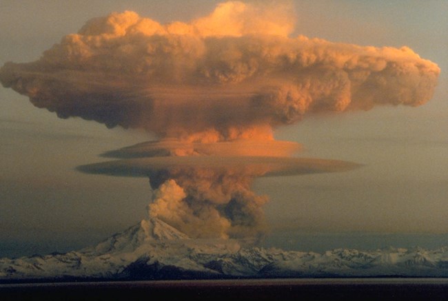 Image of an ash cloud looming above an active volcano during an eruption.