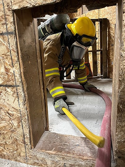 Firefighter crawls around a tight hallway.