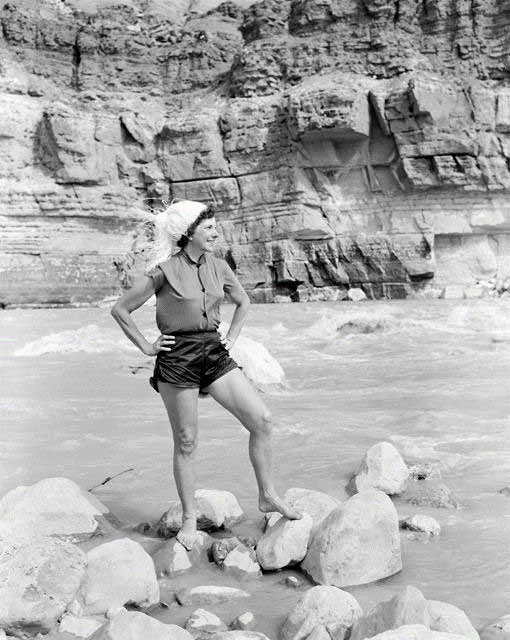 Georgie White stands on rocks in the Colorado River.