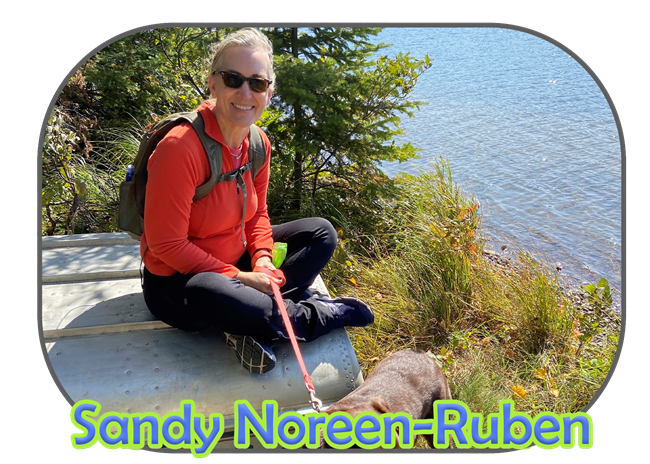 Volunteer Sandy Noreen-Ruben sitting on a boat next to the river with her dog.