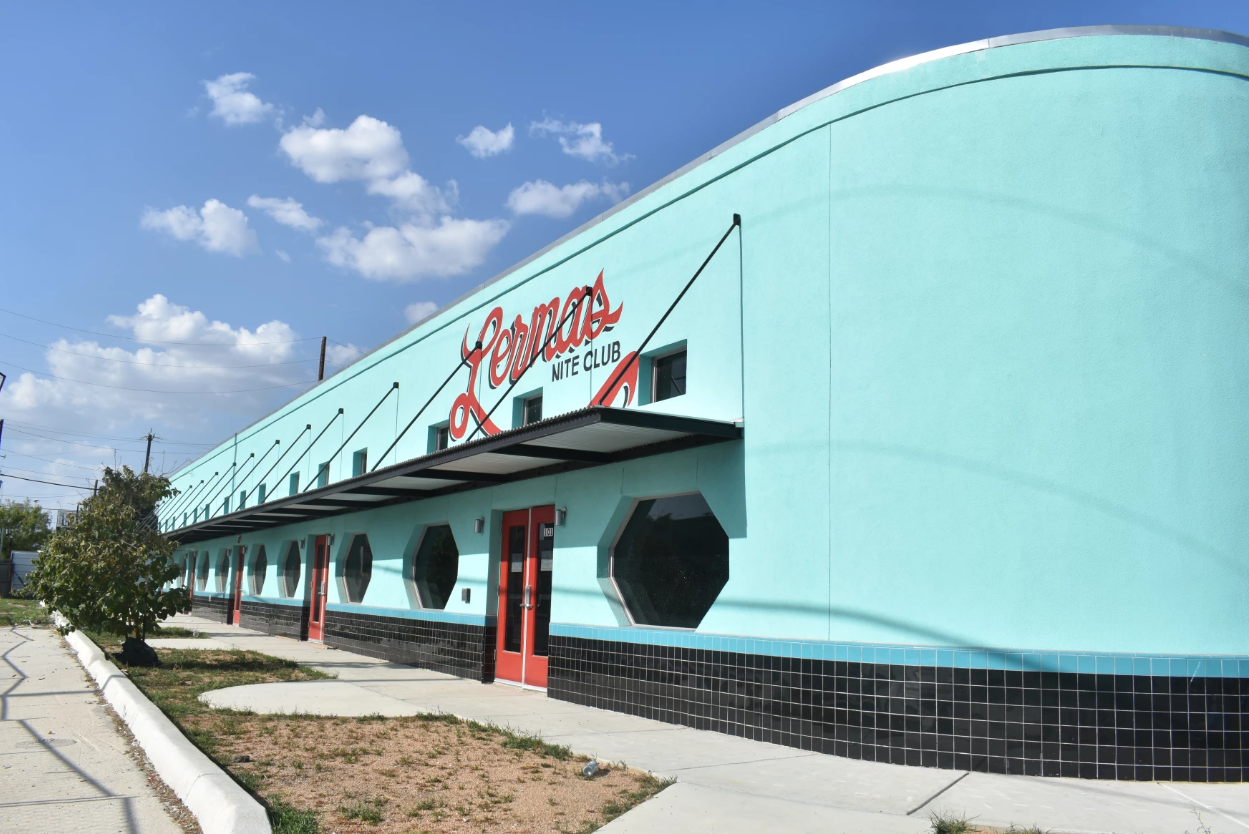 Side profile of blue building with red accent marks and a black and white tile border along the bottom of building