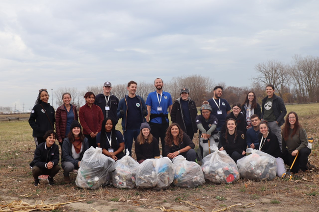 A group of Community Volunteer Ambassadors and Conservation Legacy staff pose with full garbage bags from a volunteer service project.