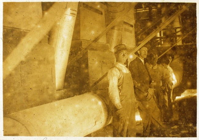 Black and white men standing next to a large machine