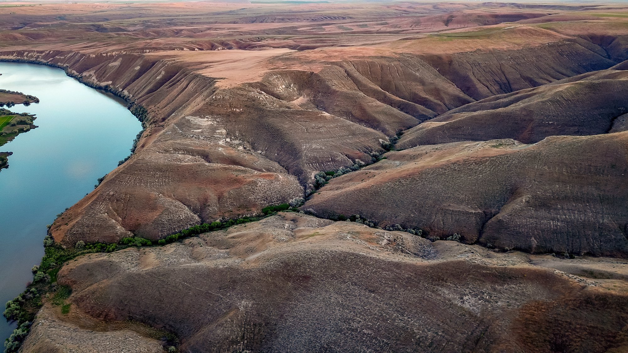 A turquoise blue Snake River flows through the brown hills at Hagerman Fossil Beds National Monument.