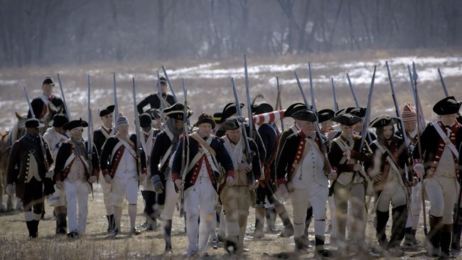 tired-looking continental army soldiers march through a frozen field