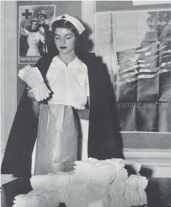 young woman in nurse uniform packing supplies while standing in front of world war two posters