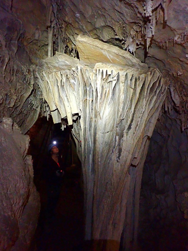 A 10 foot diameter cave shield with a researcher shining a light from the side