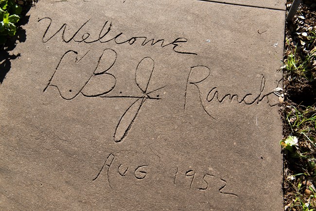 The words "Welcome LBJ Ranch August 1952" scratched into concrete.