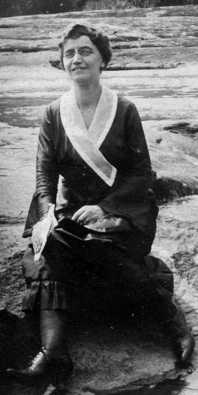 A woman, seated, outdoors, in the early 1900s