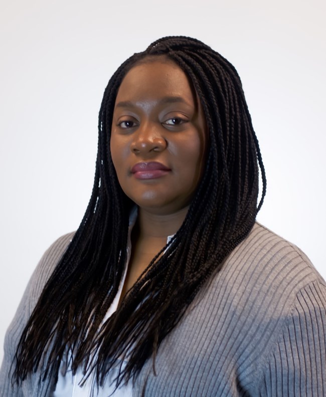 Headshot of a Black woman with braids wearing a gray cardigan