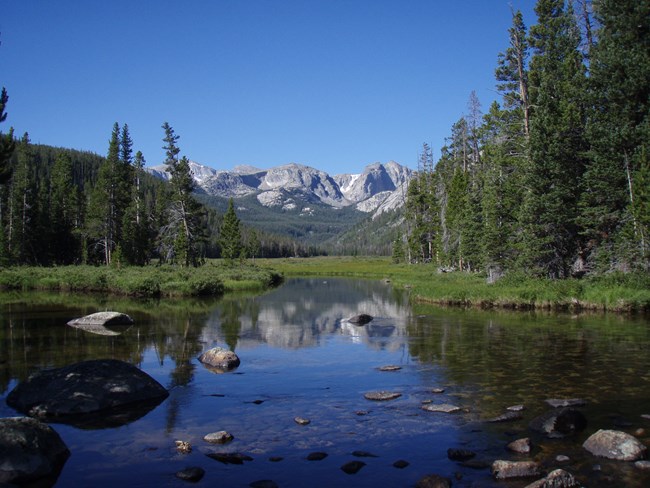 Shallow slow stream with mountains in the background.