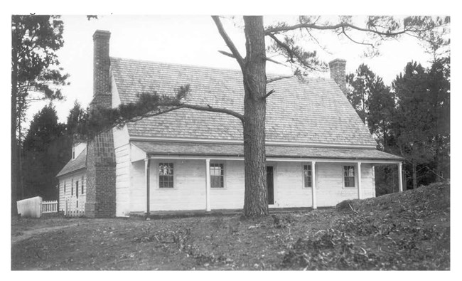 white wooden building with steep roof and chimney on either side