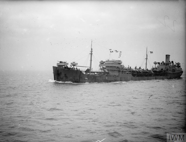 Black and white photo of an oil tanker at sea, bearing aircraft for transport