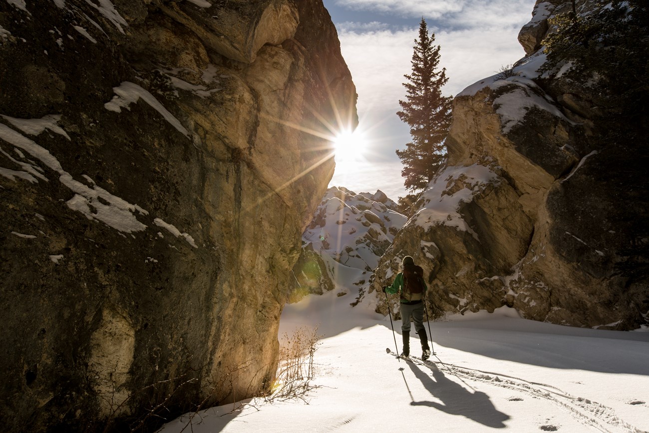 a person skiing through rocky cliffs as the sun rises