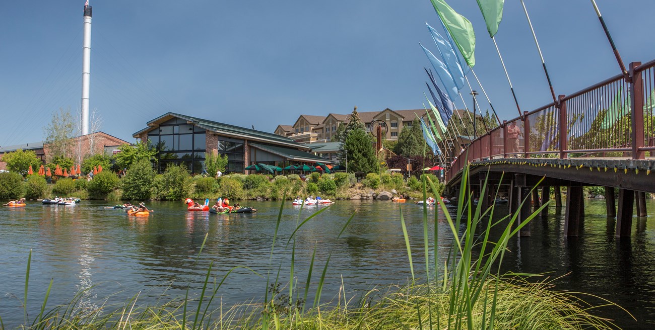 Kayakers float under a bridge on a river