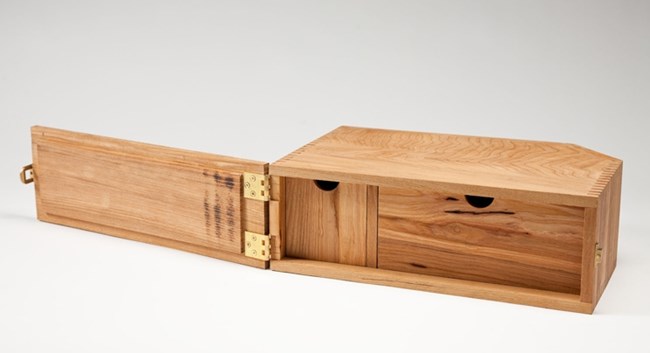 Skinny small wooden box with metal clasps allowing it to open