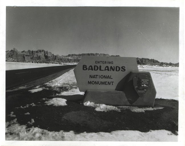a historic black and white photograph shows the original park sign reading "entering badlands national park"