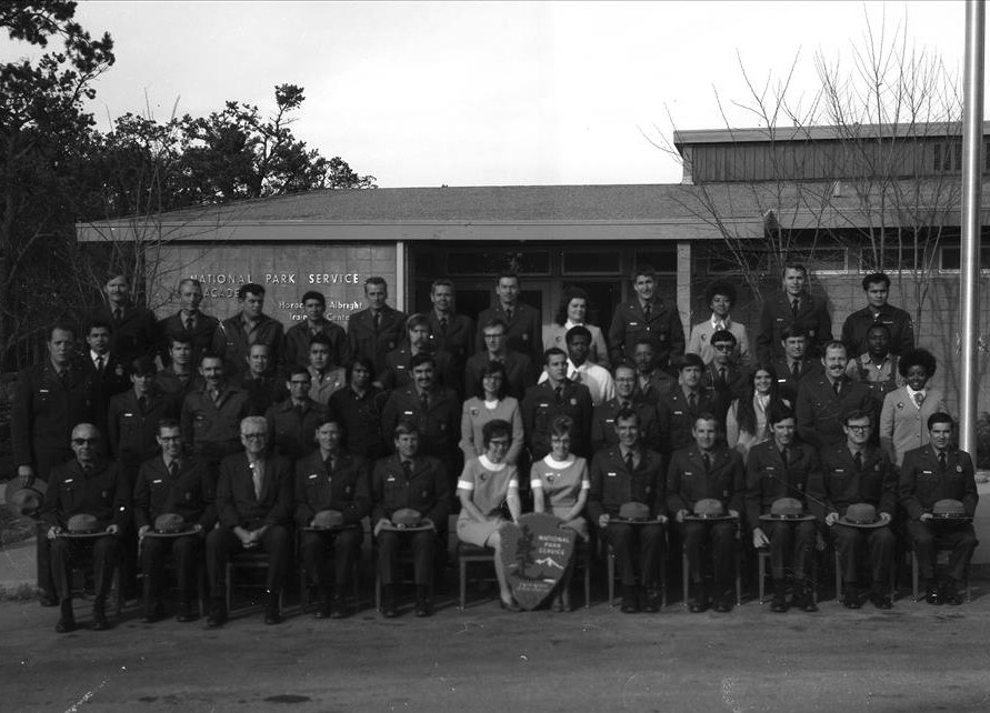 NPS employees in uniform stand outside posing for a class photo.