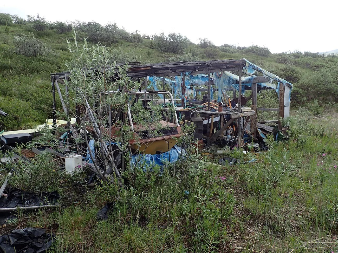Abandoned, broken, dirty mining equipment in a field.