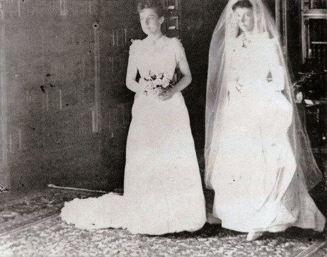 two brides standing next to each other holding flowers