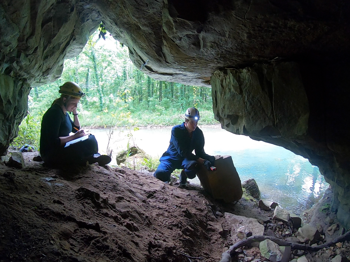 Two cavers at the entrance to a cave