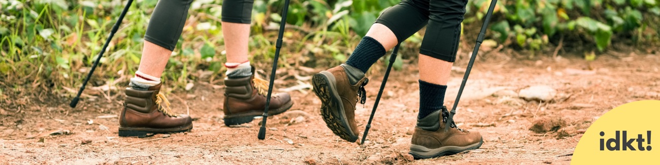 a close up of two hikers boots with hiking poles on a trail