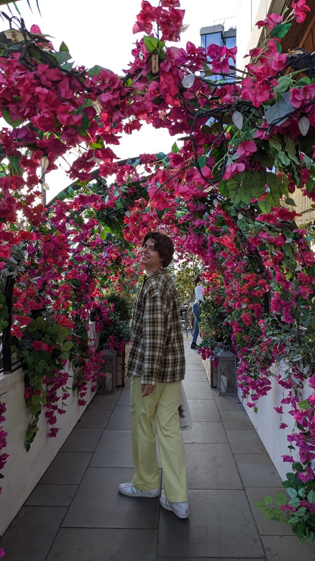 Intern standing under arches decorated with pink flowers and leaves in London