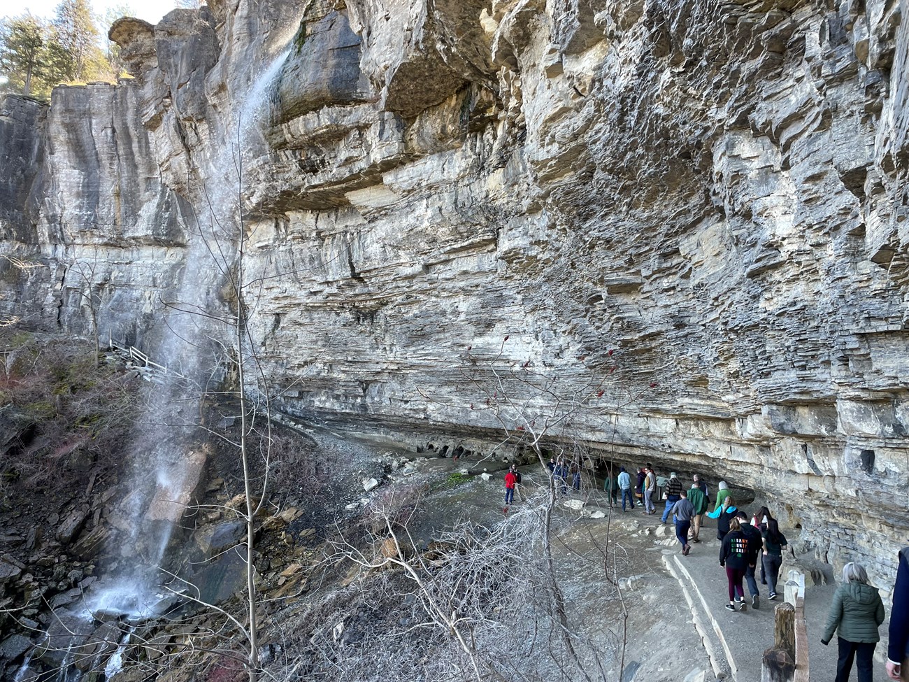 Photo of a group of people hiking under a waterfall.