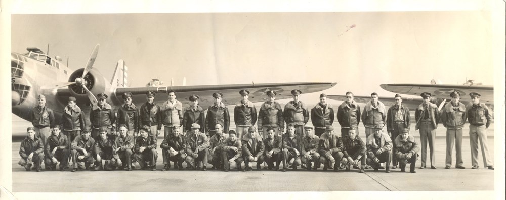 Group photo of men in uniform in front of two planes.