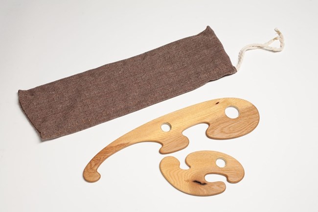 cloth pouch and two thin pieces of wood cut with curves and holes in them