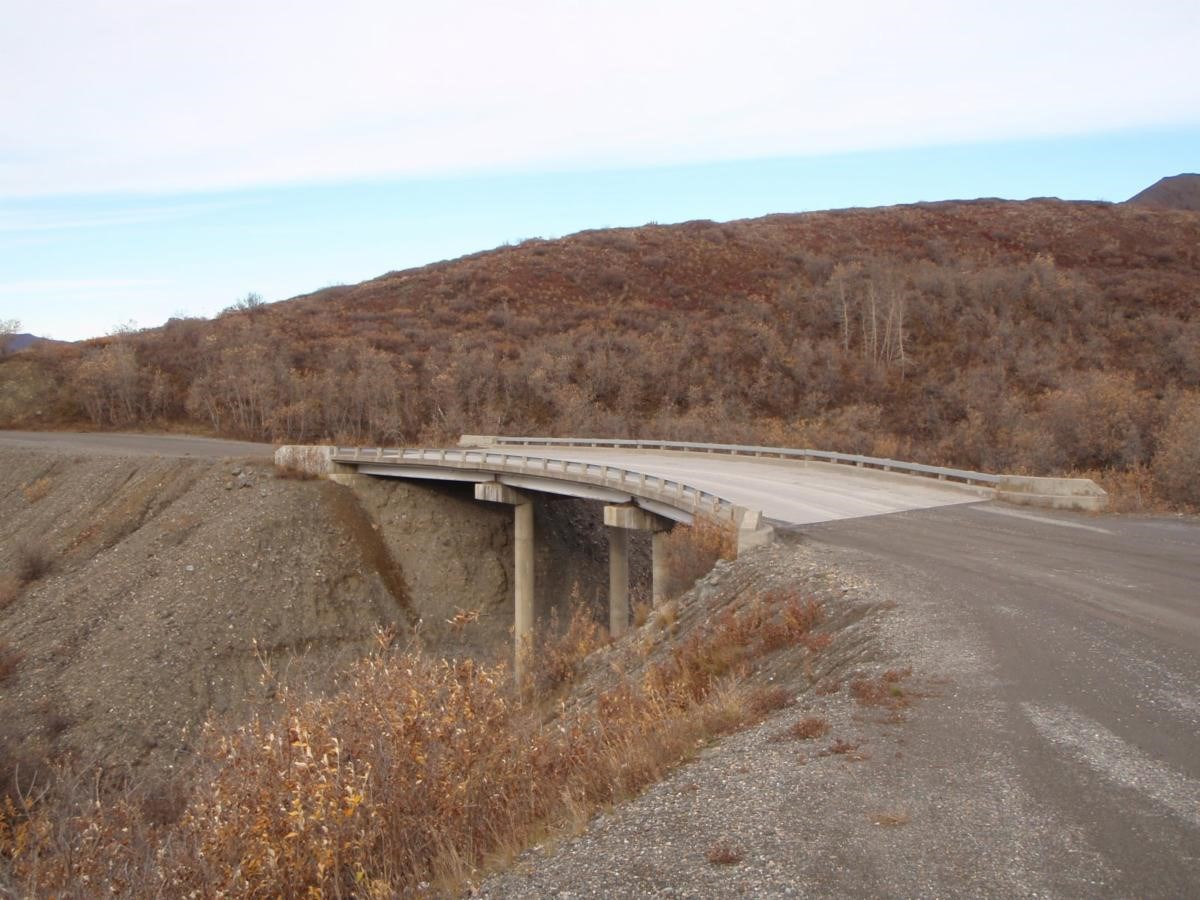 a dirt road with a bridge spanning a narrow defile