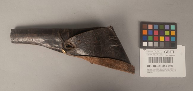 A dark brown holster on a tan surface.