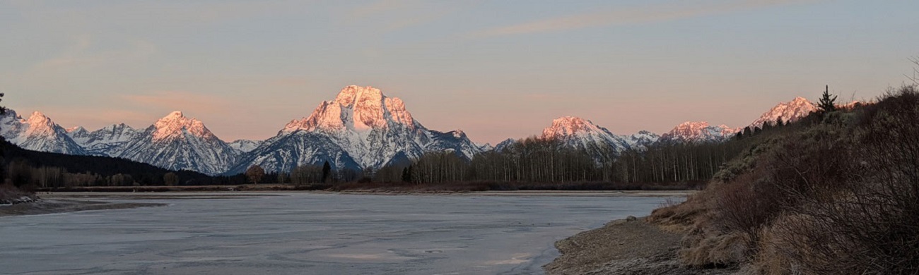 a pink sunrise over a snow covered mountain top