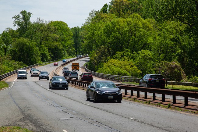 Cars driving on George Washington Memorial Parkway lined with large trees.
