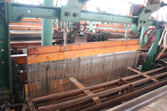 Two wooden planks with thin strips of metal hanging off the bottom are attached to a green metal structure